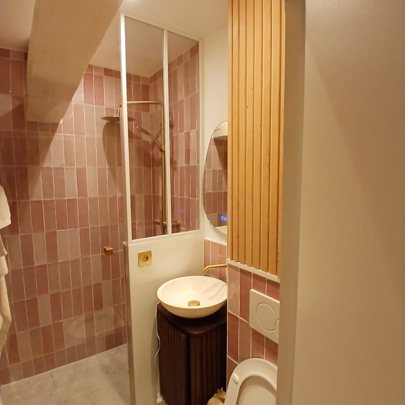 Salle d'eau en zellige rose avec verrière, vasque pierre et robinetterie laiton