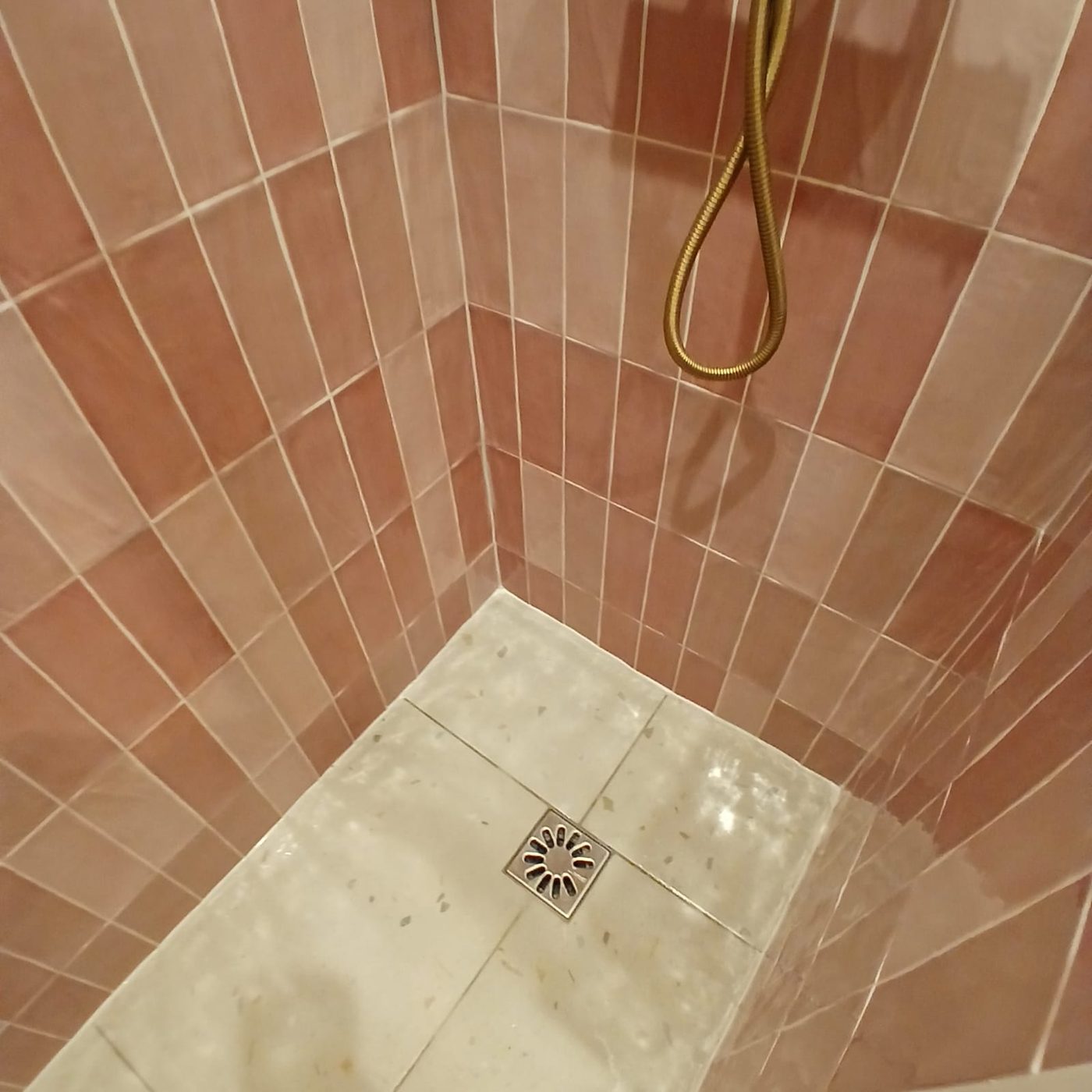 Détail de la douche à l'italienne en zellige rose avec sol en pierre