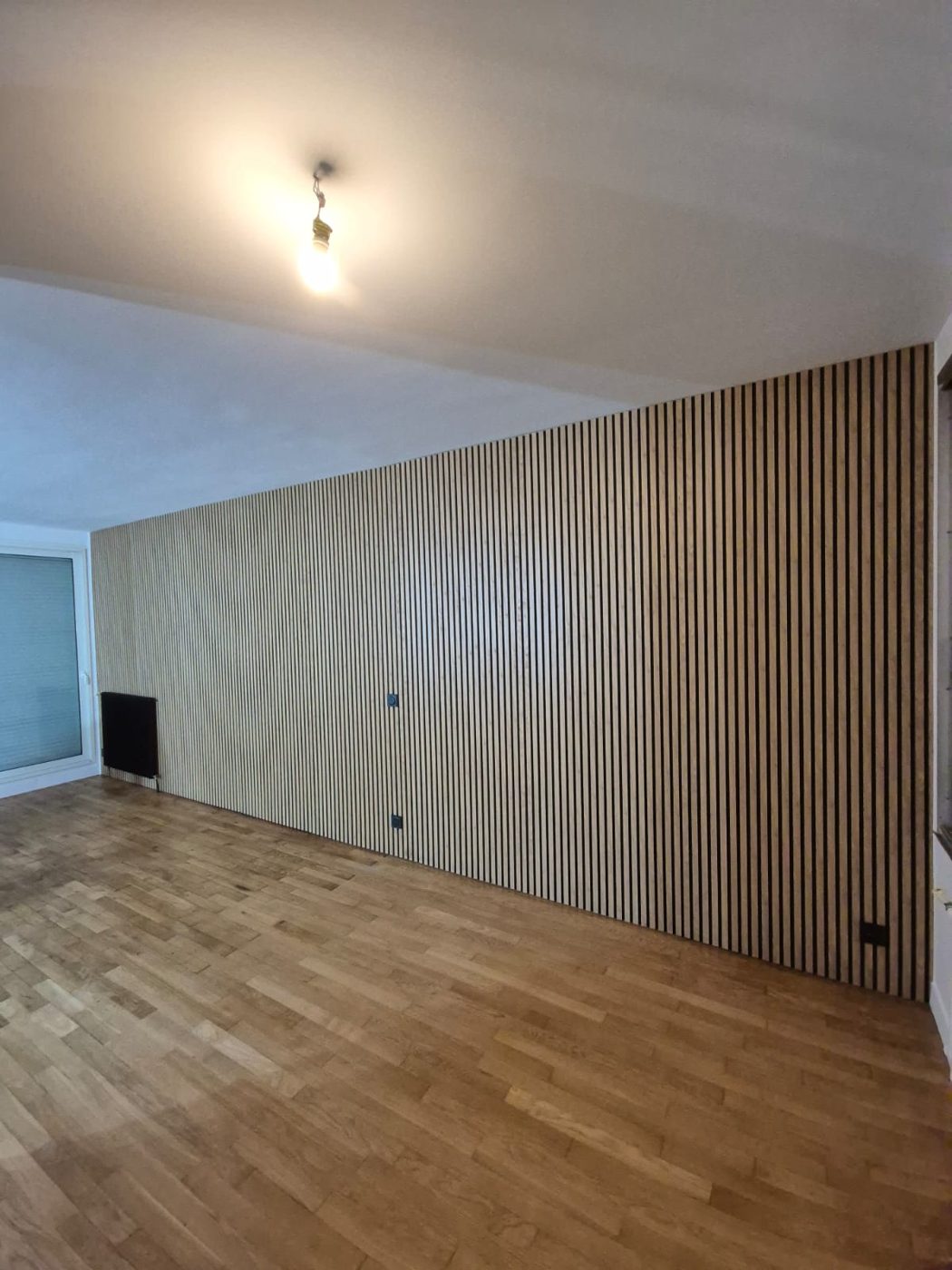 Séjour avec grand panneau mural en tasseaux de bois